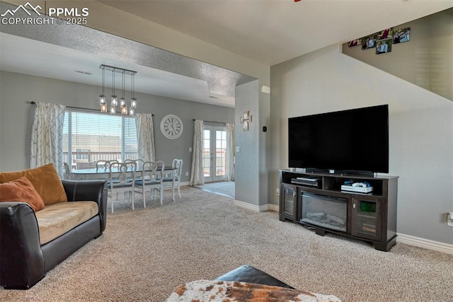 carpeted living room with french doors and a textured ceiling