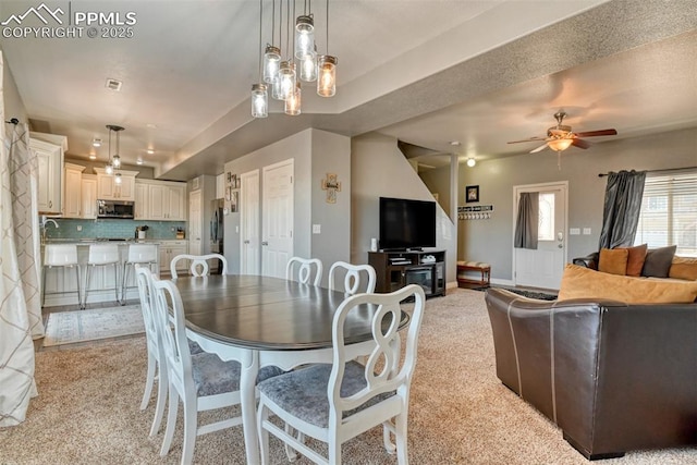 carpeted dining area with ceiling fan