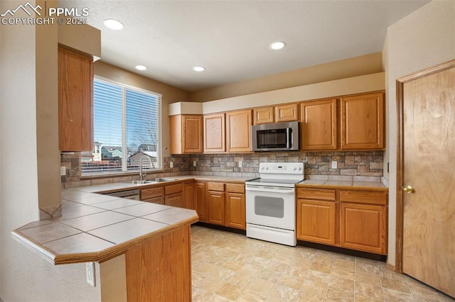 kitchen featuring sink, tile countertops, white electric stove, and decorative backsplash