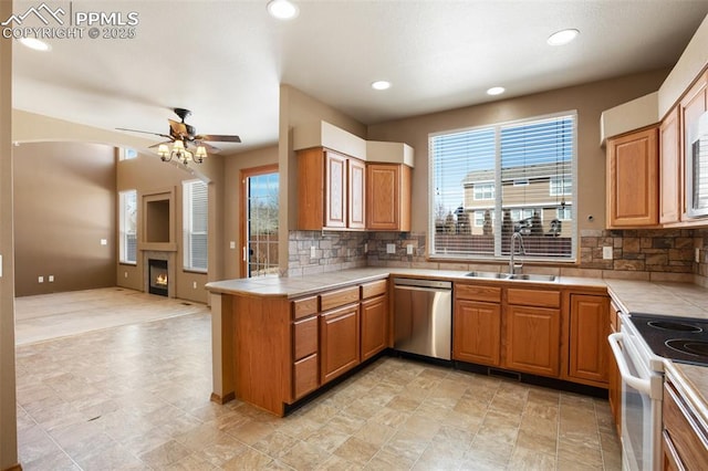 kitchen with sink, kitchen peninsula, tile counters, and dishwasher