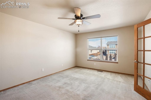 empty room with ceiling fan and light carpet