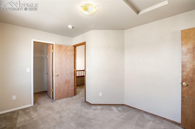 unfurnished bedroom featuring a closet, a walk in closet, and light colored carpet