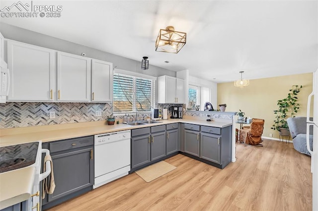 kitchen with sink, gray cabinets, backsplash, white dishwasher, and decorative light fixtures