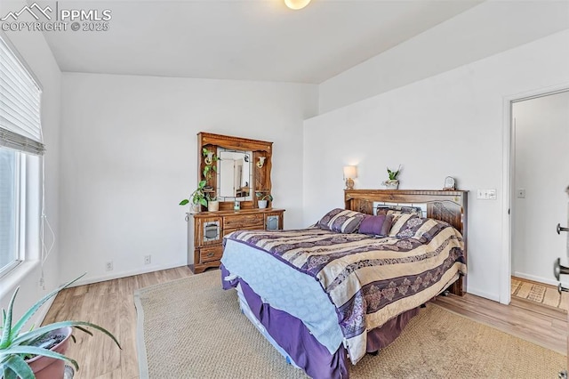 bedroom with multiple windows, vaulted ceiling, and light hardwood / wood-style flooring