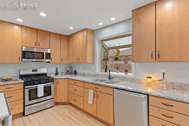 kitchen featuring sink, light hardwood / wood-style flooring, appliances with stainless steel finishes, light stone countertops, and light brown cabinetry