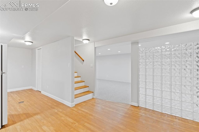 basement featuring hardwood / wood-style flooring and white fridge