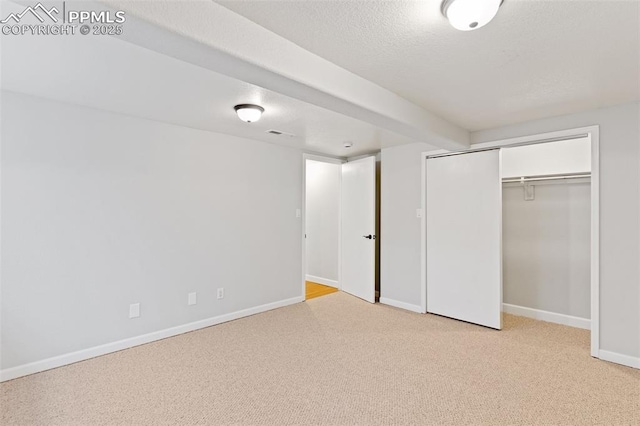 unfurnished bedroom with light carpet, a textured ceiling, and a closet