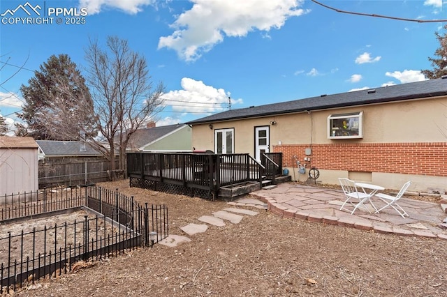 rear view of property featuring a wooden deck and a patio area