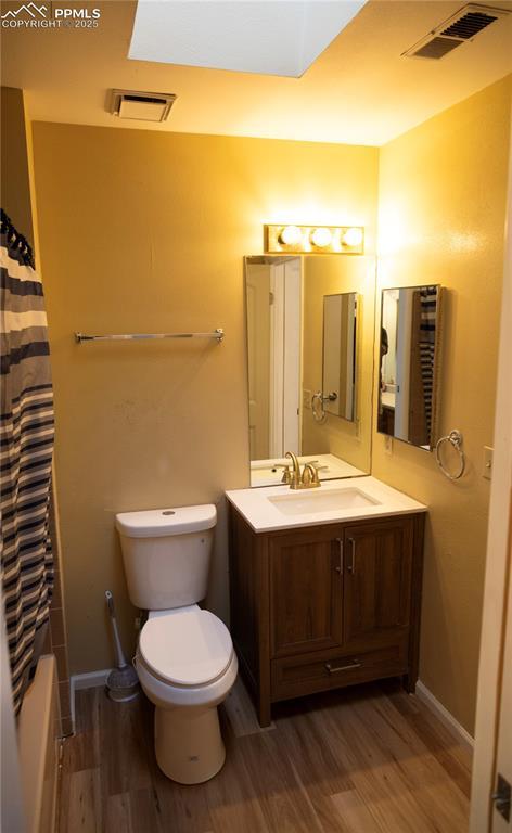 full bathroom with vanity, hardwood / wood-style flooring, toilet, and shower / tub combo with curtain