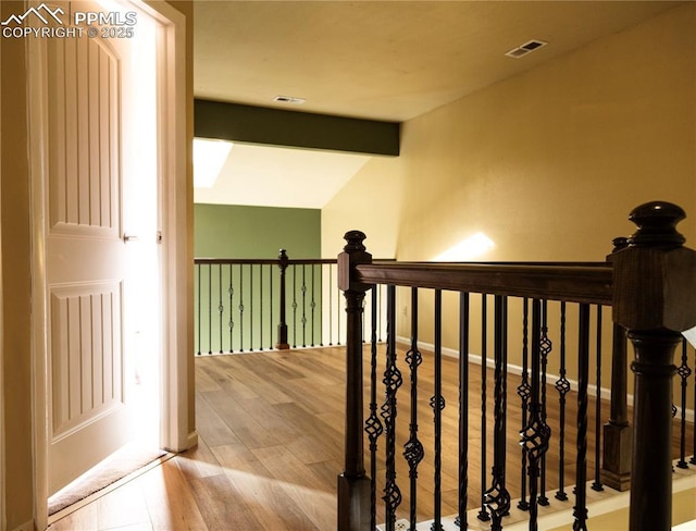 stairway featuring wood-type flooring and vaulted ceiling with beams