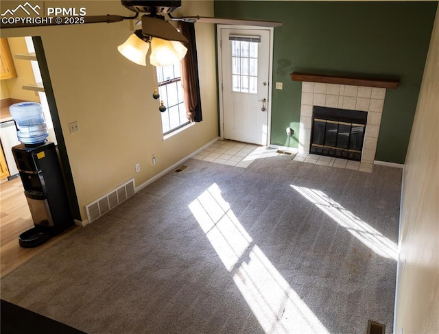 unfurnished living room with a tile fireplace and light colored carpet