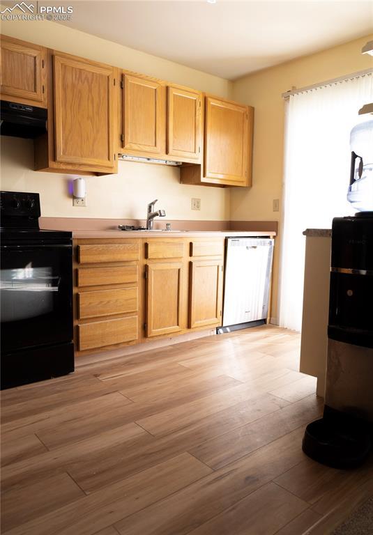 kitchen featuring sink, black electric range, light hardwood / wood-style flooring, dishwasher, and exhaust hood