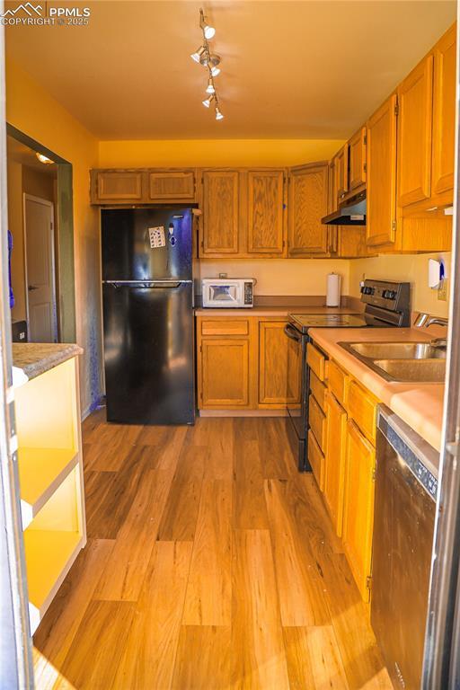 kitchen with sink, light hardwood / wood-style floors, and black appliances