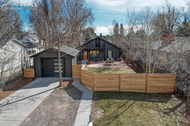 view of front of home featuring an outbuilding, a fenced front yard, a garage, driveway, and board and batten siding