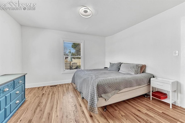 bedroom with light wood-type flooring and baseboards