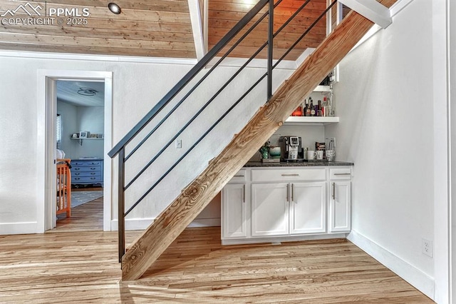 bar with stairway, baseboards, light wood-style flooring, and a dry bar