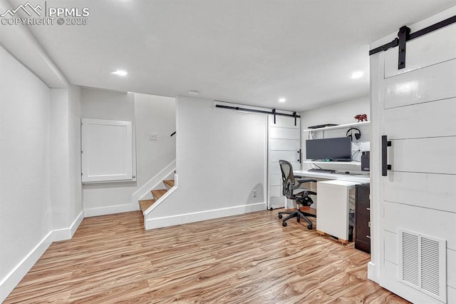 office area with a barn door, visible vents, baseboards, light wood-type flooring, and recessed lighting