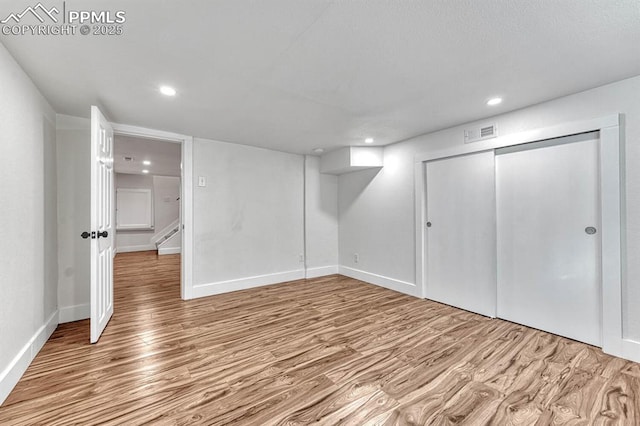 finished below grade area featuring stairs, visible vents, wood finished floors, and recessed lighting