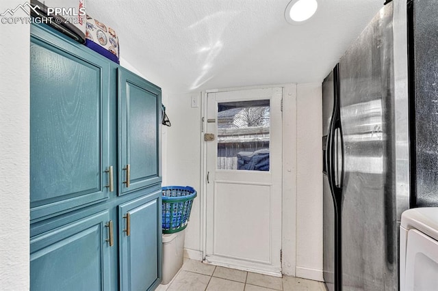 washroom featuring a textured ceiling, light tile patterned flooring, and washer / dryer