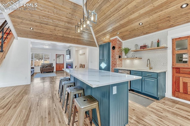 kitchen featuring light wood-style flooring, open floor plan, a kitchen breakfast bar, blue cabinetry, and a sink