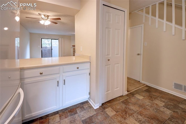 kitchen featuring white cabinetry, a textured ceiling, and ceiling fan