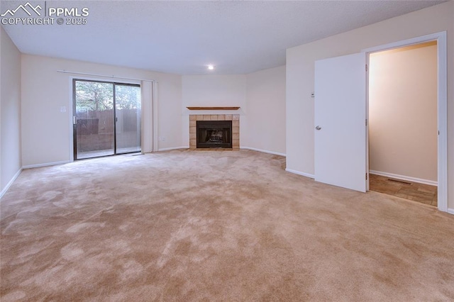 unfurnished living room featuring light colored carpet and a tile fireplace