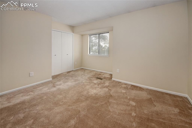 unfurnished bedroom featuring light carpet and a closet