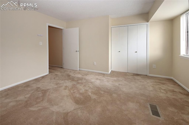 unfurnished bedroom with light colored carpet and a closet