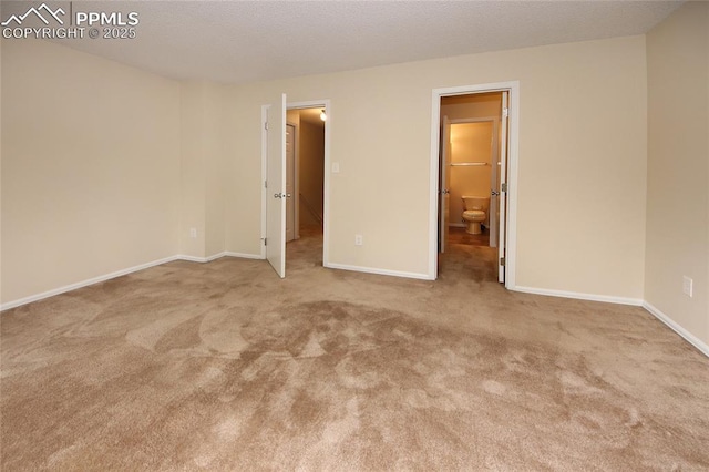 unfurnished bedroom featuring light colored carpet and ensuite bath