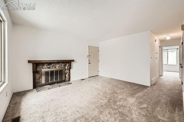 unfurnished living room featuring a fireplace, carpet floors, and a textured ceiling