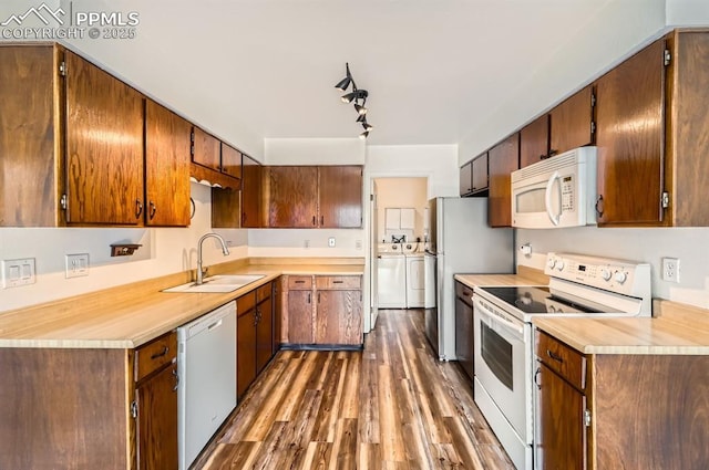 kitchen featuring sink, dark wood-type flooring, washing machine and clothes dryer, and white appliances