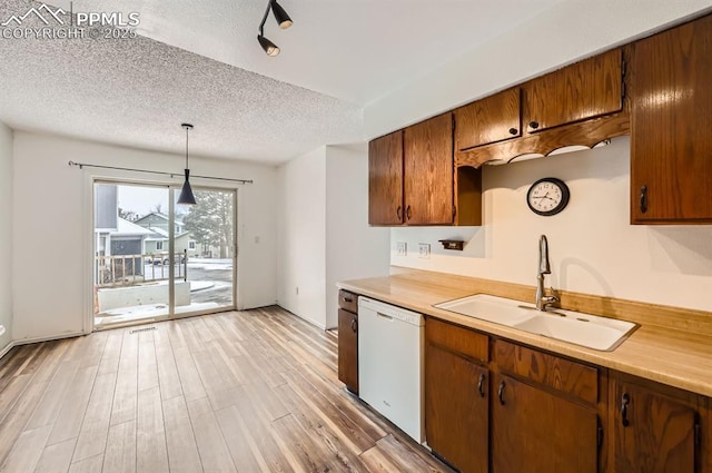 kitchen with sink, hanging light fixtures, white dishwasher, light hardwood / wood-style floors, and a textured ceiling