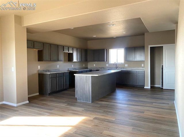 kitchen with hardwood / wood-style floors, a kitchen island, and gray cabinetry