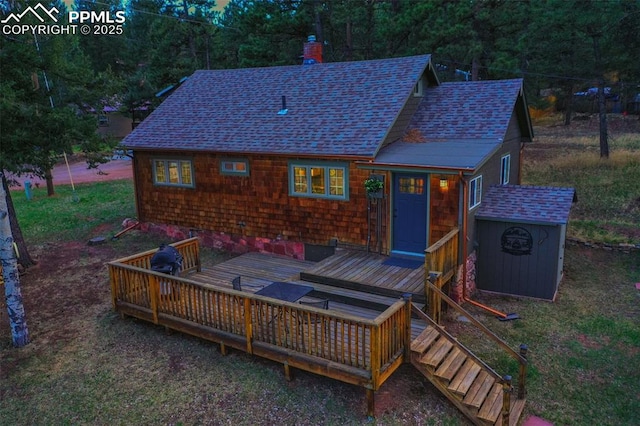 back of house with a deck and a storage unit