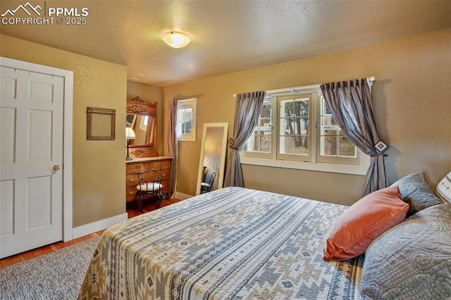 bedroom with multiple windows, hardwood / wood-style floors, and a textured ceiling