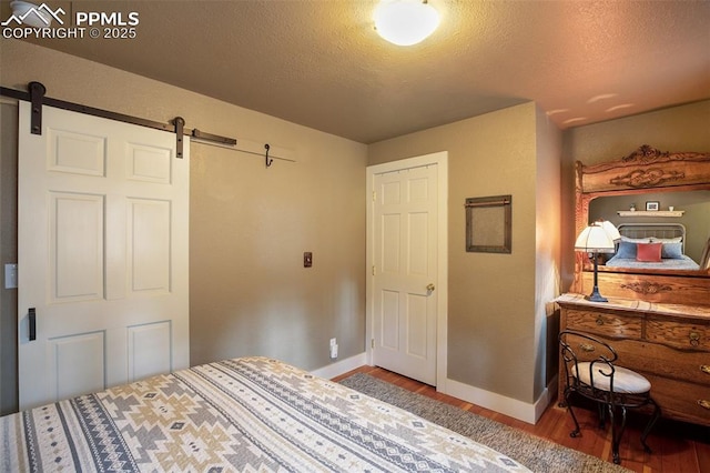 bedroom featuring hardwood / wood-style flooring, a barn door, and a textured ceiling