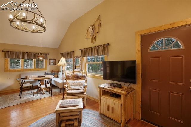 living room with vaulted ceiling, a chandelier, and light hardwood / wood-style floors