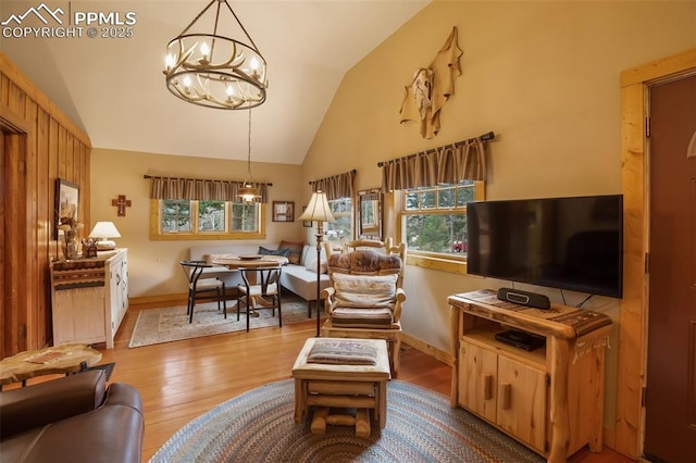 living room featuring vaulted ceiling, a notable chandelier, and light wood-type flooring