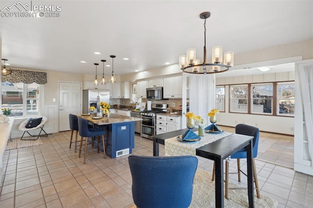 kitchen featuring appliances with stainless steel finishes, hanging light fixtures, a kitchen breakfast bar, a kitchen island, and white cabinetry