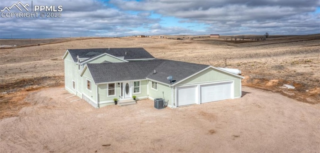 view of front of home featuring cooling unit, a garage, and a rural view