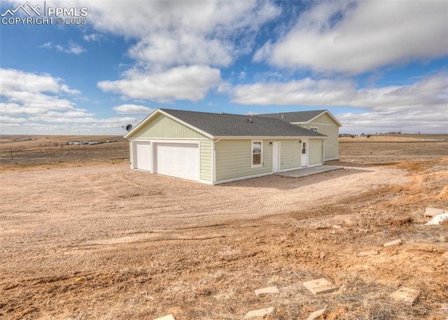 view of front of house with a garage and a rural view