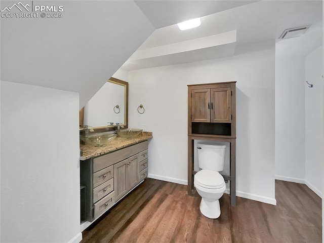 bathroom featuring toilet, vanity, hardwood / wood-style floors, and vaulted ceiling