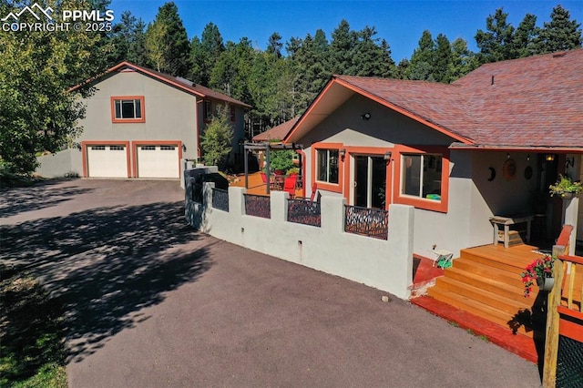 view of home's exterior featuring a fenced front yard, a detached garage, a shingled roof, and stucco siding