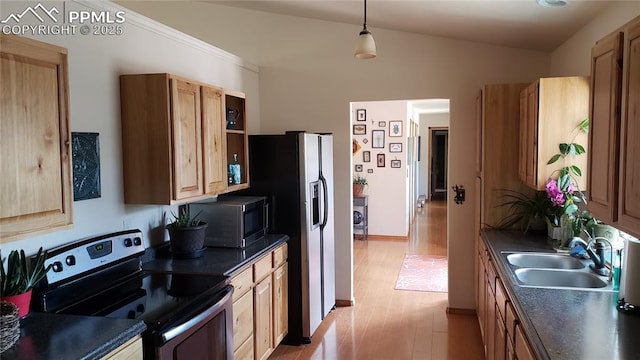 kitchen with pendant lighting, stainless steel appliances, dark countertops, a sink, and light wood-type flooring