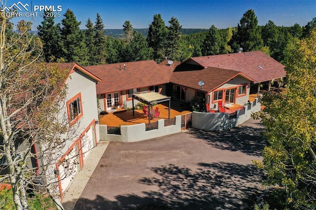 exterior space with stucco siding, a patio area, a wooded view, a garage, and driveway