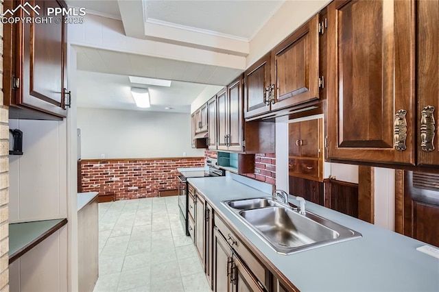 kitchen featuring crown molding, brick wall, sink, and electric range