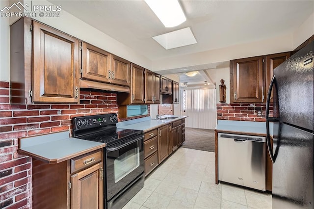 kitchen with brick wall, a skylight, sink, and black appliances