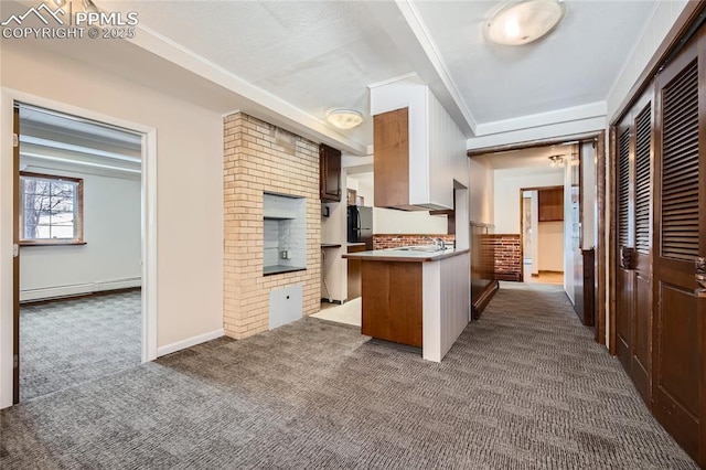 kitchen with a baseboard radiator, sink, dark colored carpet, kitchen peninsula, and black fridge