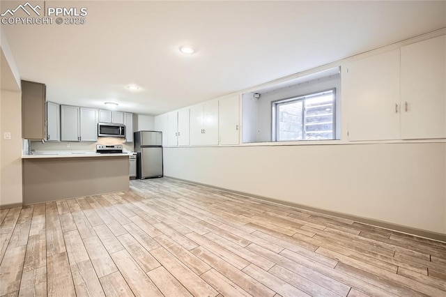 kitchen featuring light hardwood / wood-style flooring, kitchen peninsula, and appliances with stainless steel finishes