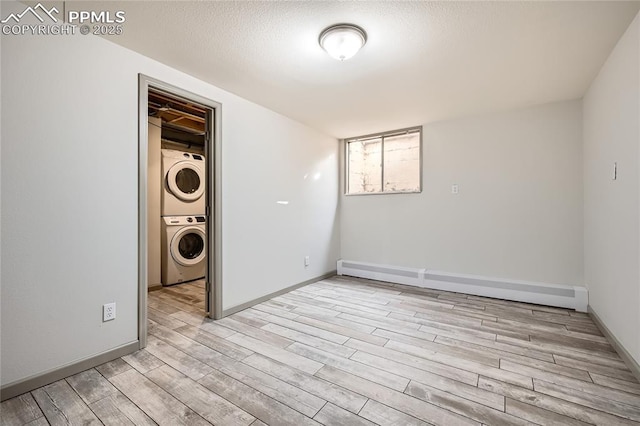 laundry room featuring a baseboard heating unit, light hardwood / wood-style flooring, a textured ceiling, and stacked washing maching and dryer